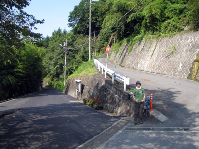 登山道へ続く、つづら折れの坂道の折り返し点に立つ隊員。舗装された道は照り返しで暑さを倍増させます